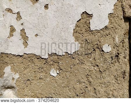 Close-up Background Of The Wall Of An Old House Made Of Clay Mixed With Straw. Old Type Of Construct