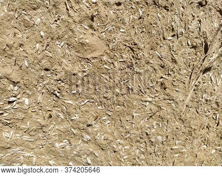 Close-up Background Of The Wall Of An Old House Made Of Clay Mixed With Straw. Old Type Of Construct