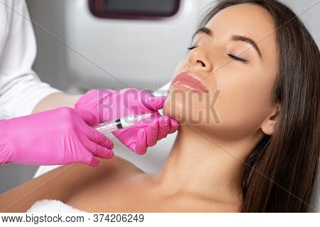 Cosmetologist Makes Lipolytic Injections To Burn Fat On The Chin, Cheeks And Neck Of A Woman Against