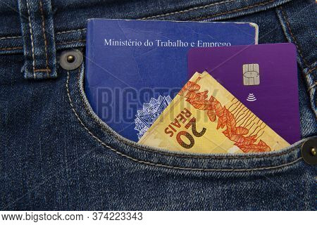 Close Up Of Cellphone In The Front Pocket Of Jeans, Credit Cards And Brazilian Banknotes. Translate: