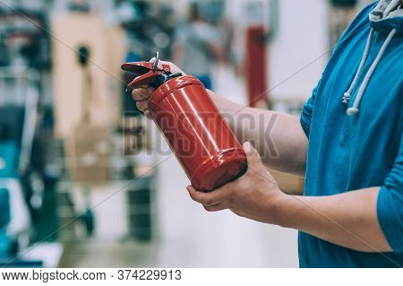 A Man Holds A Fire Extinguisher In His Hand. A Buyer In A Hardware Store Selects A Product.