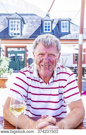 Handsome Mature Man Sitting Outside In A Beergarden And Enjoys Life