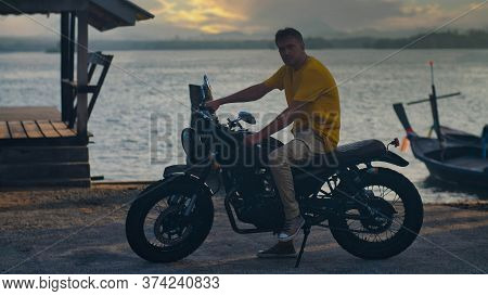 Handsome Man In Yellow T-shirt Sitting On Motorbike On Ocean Beach