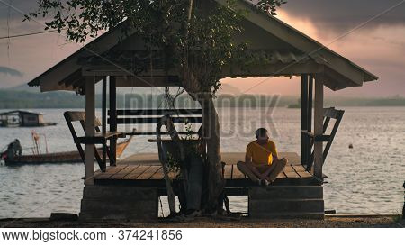 A Handsome Man In Yellow T-shirt Meditate In Arbor In Sunset