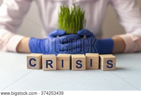 Crisis Inscription On Wooden Cubes On Light Rable With Blurring Background Of Protective Gloves And 