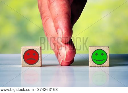 The Hand Separates Two Wooden Blocki With Red Sad Face And Green Happy Face. Symbol For The Differen