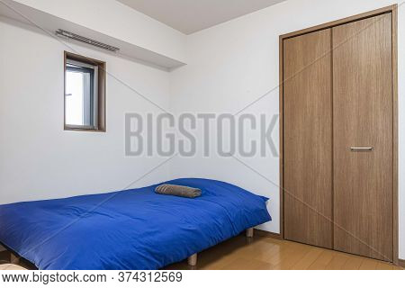 Single Bed And Dark Blue Blanket In A Small Bedroom For Single People