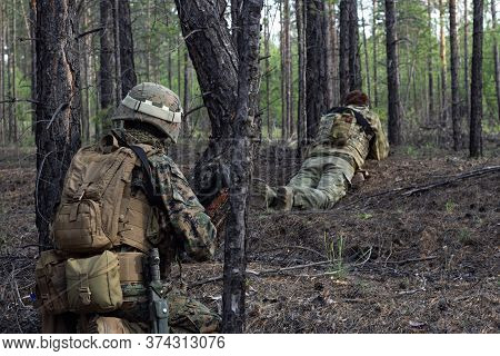 Two American Soldiers Are On A Stakeout In The Summer Forest, Waiting For The Enemy, Active Military