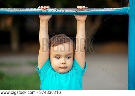 Toddler Boy Learning To Do Pull Ups At Gym Lesson In Kindergarten: Preschooler Hanging On Worn-out S
