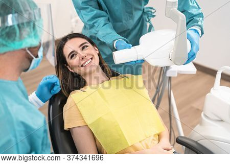 Man Dentist Operating Young Smiling Woman In Dental Clinic - Oral Healthcare Assistance Concept