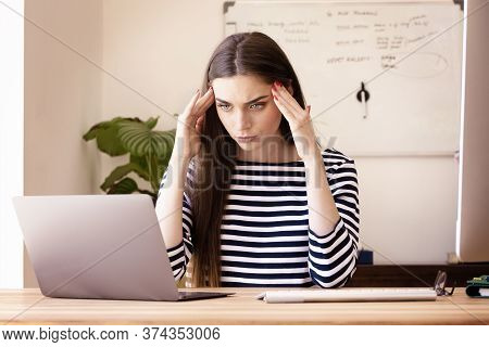 Portrait Of Beautiful Young Woman Having A Headache While Sitting At Desk And Working