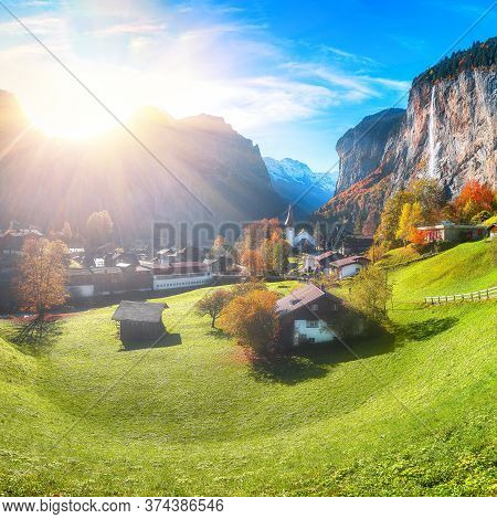 Stunning Autumn Landscape Of  Alpine Village Lauterbrunnen With Famous Church And Staubbach Waterfal
