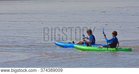 Felixstowe, Suffolk, England - June 24, 2020:  Boys Paddling Kayaks In Streams Between Mud Flats.