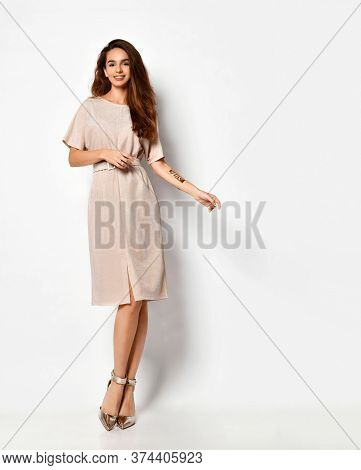 Tender Long-haired Young Woman Posing In Knee-length Light Powder-pink Dress With Belt And Silver Hi