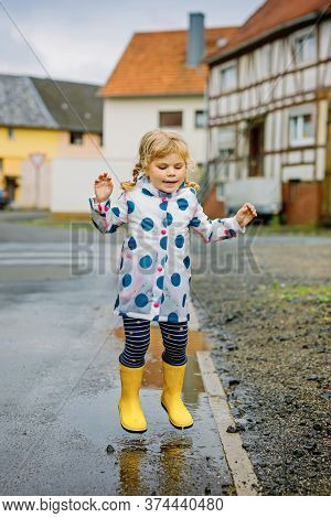 Little Toddler Girl Wearing Yellow Rain Boots, Running And Walking During Sleet On Rainy Cloudy Day.