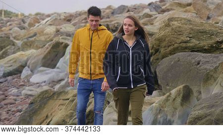 Couple Walks Along The Rocky Beach Of Rossbeigh