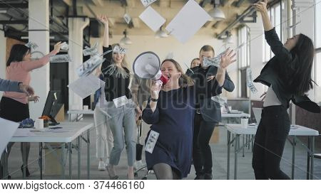 Colleagues Perform A Hand Dance In The Office During A Break. A Man Rolls An Employee In A Chair, Co