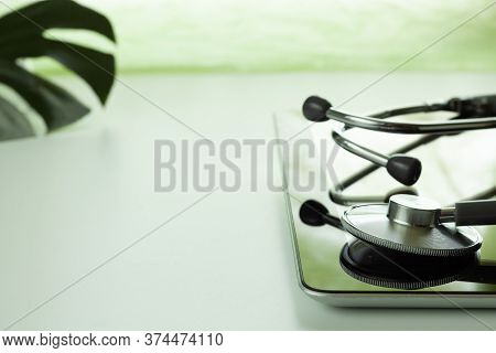 Statoscope And Tablet Computer On A White Table, Online Medical Consultation, Leaf Of A Tropical Mon