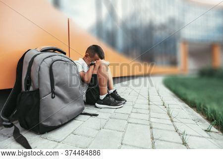 child with backpack in depression is sitting on the floor doesn't want back to school