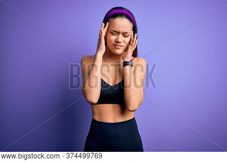 Young beautiful sporty girl doing sport wearing sportswear over isolated purple background with hand on headache because stress. Suffering migraine.
