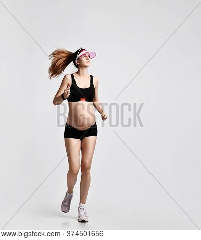 Pregnant Girl With Belly, In Green Sun Visor, Black Sport Shorts And Top, Pink Sneakers. She Is Jogg
