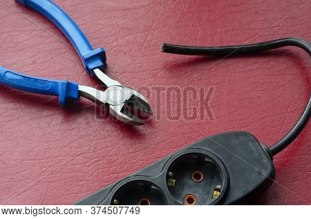 Nippers With A Blue Handle And An Electric Splitter With A Cut Cable. Emergency Shutdown Of The Cons