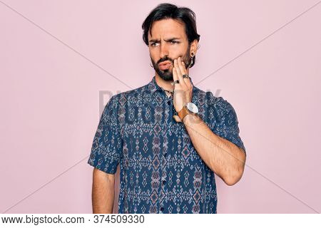 Young handsome hispanic bohemian man wearing hippie style over pink background touching mouth with hand with painful expression because of toothache or dental illness on teeth. Dentist