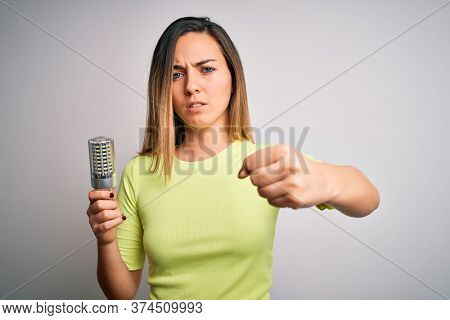 Young beautiful blonde woman holding led lightbulb over isolated white background annoyed and frustrated shouting with anger, crazy and yelling with raised hand, anger concept
