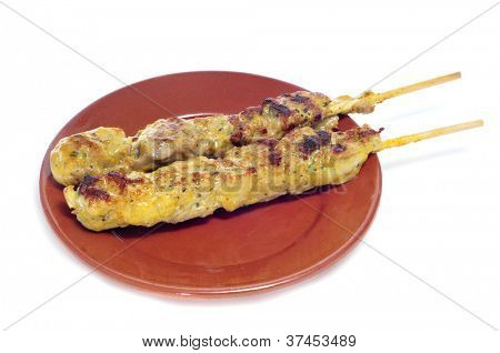 Nærbillede af en plade med pinchos de pollo, spanske kylling spyd, på en hvid baggrund