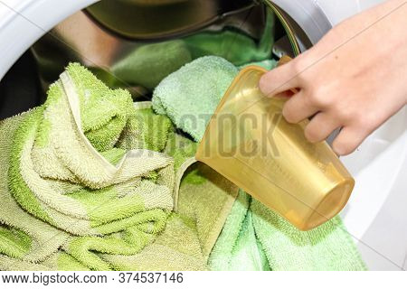 A Woman's Hand Adds Washing Powder To The Washing Machine With Dirty Laundry. Close-up, Selective Fo