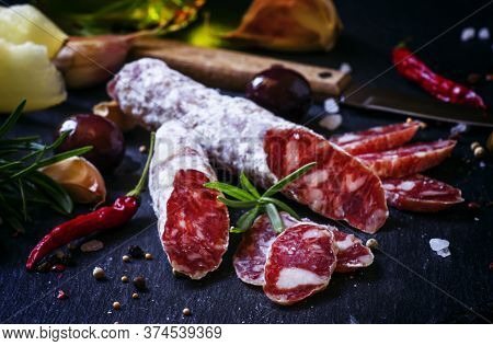 Jerked Italian Salami With Rosemary, Spices, Olives And Oil. Dark Vintage Background, Low Key, Selec