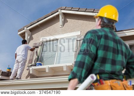 Contractor Overlooking Painter Paitning House.