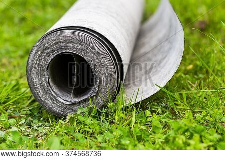 Roll Of Roofing Felt Close-up. Ruberoid On The Green Grass. A Beautiful Image Of Building Material. 