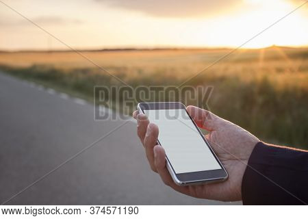 Man With A Mobile Phone In Hand Using Navigator App At Sunset