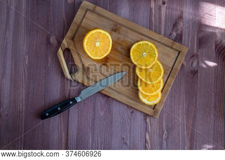 Orange And Knife On A Wooden Board