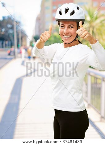 Femme portant casque montrant le pouce vers le haut, en plein air