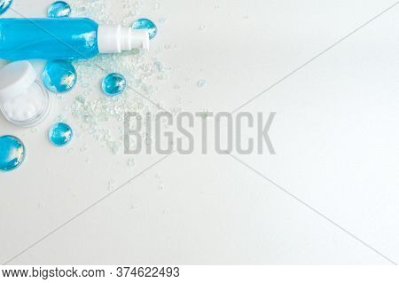 Blue Gel Spray, Drops, Glass, Bath Salt And Moisturizer On A White Background, Top View. Copy Space