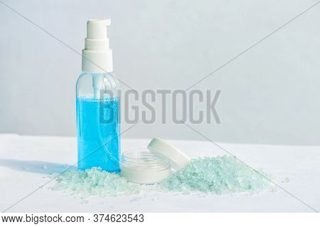 Blue Gel In A Bottle, White Cup, Blue Bath Salt, Cream In A Jar On A White Background.