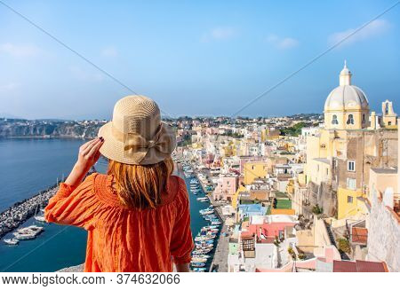 Beautiful Young Girl With Hat Looking At Stunning Panoramic View Of Procida Island, Naples, Italy