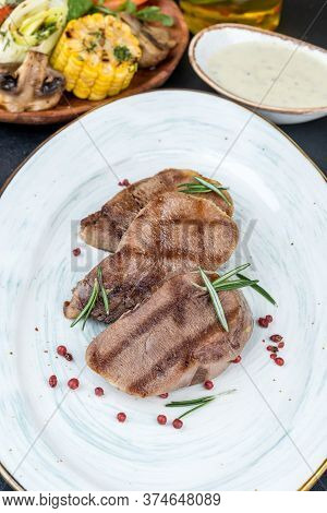 Grilled Veal Tongue Served On A White Plate