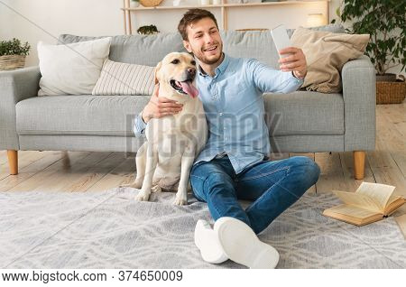 Best Friends Concept. Happy Bearded Man Taking Selfportrait With Labarador Sitting On The Floor In M