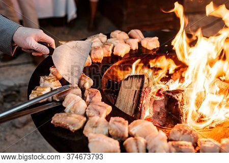 A Close-up Of The Chefs Hands Flipping Fish Steaks With A Spatula And Tongs.