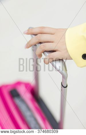Cropped Shot Of Female Hand Carrying A Pink Suitcase Over White Background With Copyspace.