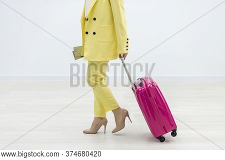 Cropped Shot Of Female Carrying A Pink Suitcase And Pssport Over White Background With Copyspace.