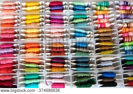 Floss Threads Dmc Arranged By Color In A Transparent Plastic Box.
