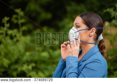 Beautiful Girl Puts A Medical Mask On Her Face On The Nature. Coronavirus And Covid-19 Protection