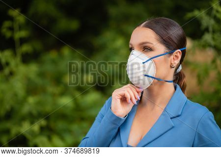 A Beautiful Woman Is Standing In The Street In A Medical Mask On Her Face Made Of Nanofiber. Coronav