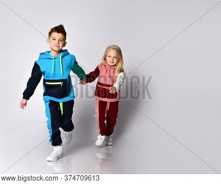 Little Boy And Girl In Sportsuits Walking Forward Hand In Hand. Young Athletes, Being Stylish, Frien