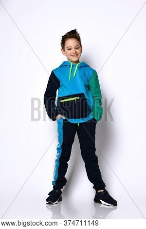Sly Active Smiling Baby In A Modern Cotton Tracksuit With A Cute Haircut, Hands In Pockets. Stylish 