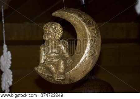 Angel Figure Sitting On Crescent Shaped Moon